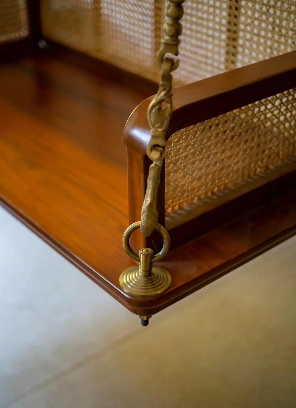 Traditional brass chain detail on a teak swing with cane woven backrest